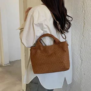 Detalle de bolso de hombro trenzado marrón, bolso tote casual elegante para el día a día.