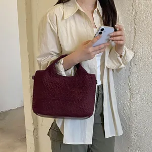 Vista detallada del bolso tote de cuero tejido en burdeos, mostrando su textura y estilo.