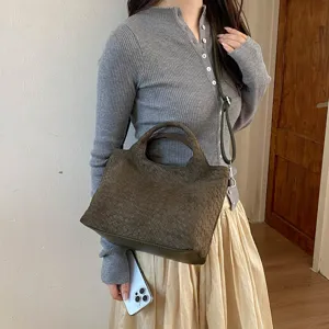Vista detallada del bolso tote tejido en verde oscuro llevado por el modelo, estilo casual.