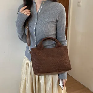Vista detallada del bolso tote tejido marrón, mostrando textura premium y diseño práctico.