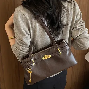 Detailansicht der vintage braunen Schultertasche mit eleganter goldener Hardware und Anhänger.