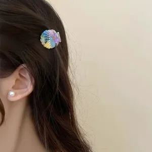 Kleiner bunter, schillernder Muschel-Haarclip, getragen auf dunklem Haar im Detail.