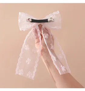 Gedetailleerd overzicht van elegante witte kanten strik haarclip met veerclip
