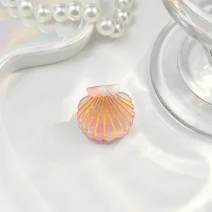 Nahaufnahme einer Mini-Haarklammer in Muschelform mit rosa Farbverlauf und Goldglitzer.