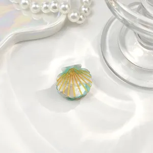 Nahaufnahme einer mini mintgrünen Haarklammer in Muschelform mit goldenem Glitzer-Akzent