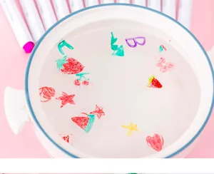Detail view of magical water floating pens demonstrating colorful ink shapes floating on water surface.