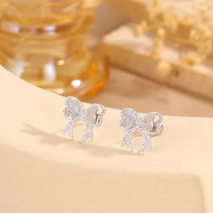 Close-up detail shot of sparkling silver bow earrings with pave stones, elegant design.