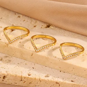 Detail shot of V-shaped gold plated rings with sparkling pave cubic zirconia stones on stone.