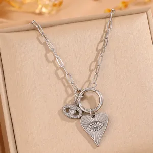 Close-up detail of silver titanium steel evil eye and sunburst heart pendant necklace.