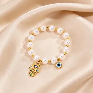 Closeup view of the gold stainless steel Hamsa hand and eye pearl bracelet details.