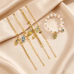 Gold Hamsa hand evil eye bracelet set featuring dainty chains and pearl beaded design detail.