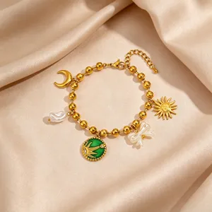 Detailed shot of retro gold stainless steel charm bracelet with sun, moon, pearl and bow.