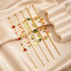 Stainless steel fruit charm bracelet detail, elegant gold plated jewelry close-up view.