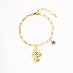 Close up detail of golden stainless steel hamsa hand and evil eye charm link bracelet jewelry.