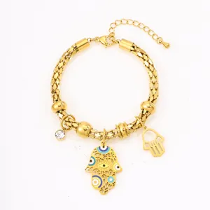 Gold stainless steel hamsa hand evil eye bracelet detail view, shiny metallic texture charm chain.