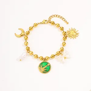 Gold multi-charm bracelet detail showing sun, moon, pearl, and green pendant charms.