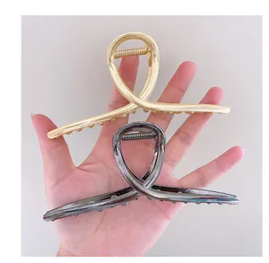 Detail view of large metal hair claw clips featuring a unique cross loop design in two colors.