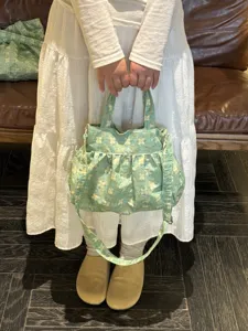 Borsa a tracolla in tela con stampa floreale, dettaglio in stile retrò con tessuto verde.