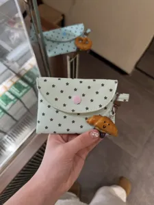 Porte-monnaie vert menthe à motif d'étoiles avec charm croissant et bouton-pression rose.