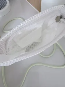 Detailed view of white mesh crossbody bag interior, showing storage space, zipper and strap.