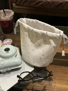 White drawstring storage bag with silver stars, detail view of cute pouch for instant camera.