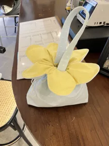 Cute floral drawstring handbag with yellow petals and blue polka dot design for daily storage.