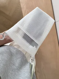 Detail view of the minimalist white mesh shoulder bag, showing textured fabric and strap rings.