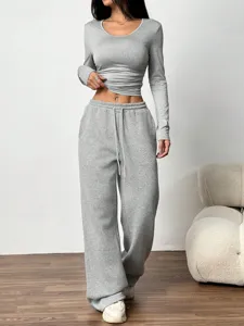 Gros plan sur les détails du haut gris à manches longues et du pantalon de survêtement.