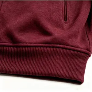 Detailansicht des bordeauxroten Fleece-Hoodies mit Rippbündchen und Reißverschlusstasche.