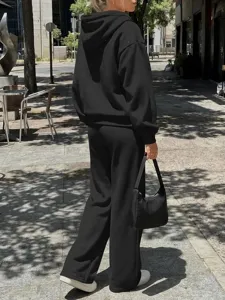 Felpa con cappuccio nera e pantaloni larghi, vista di dettaglio in stile streetwear all'aperto.