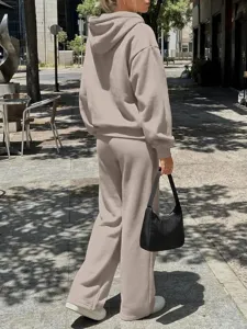 Dettaglio in esterno di una tuta casual tinta unita beige con felpa con cappuccio e pantaloni.