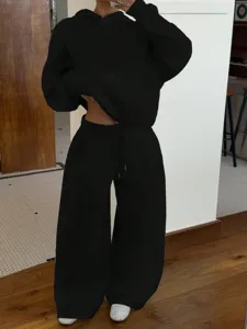 Detail shot of black fleece hoodie and sweatpants two-piece set, casual streetwear style.