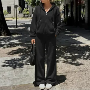 Completo felpa nera con cappuccio e zip e pantaloni della tuta ampi, stile streetwear casual.