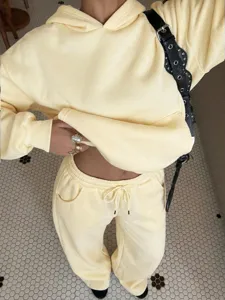 Casual pastel yellow fleece tracksuit set featuring a hooded sweatshirt and matching sweatpants.