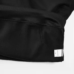 Close-up detail shot of black fleece sweatshirt hem, showing soft interior lining and label.