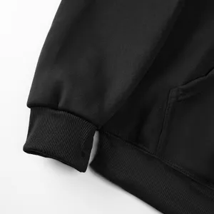 Black hoodie sweatshirt sleeve cuff and pocket detail closeup showing soft fleece fabric texture.
