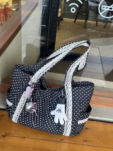 Vista detallada del bolso tote de lona negro y blanco con bonitos colgantes de dibujos.