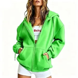 Close-up detail shot of a vibrant green zip-up hooded sweatshirt worn by a model, showing texture.