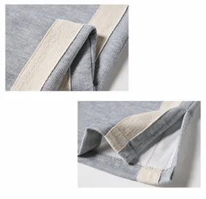 Detail view of casual men's trousers featuring side tape design and split hem stitching.