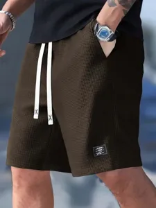 Men's casual waffle knit shorts detail featuring drawstring waist and label patch.