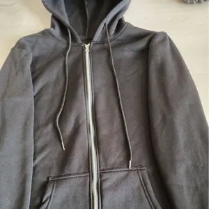 Detailed view of a solid black zip-up fleece hoodie with adjustable drawstrings and front pockets.