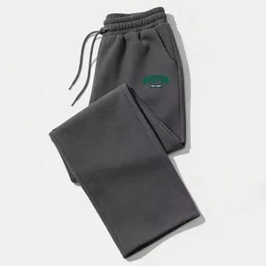 Detail of dark gray loose sweatpants featuring elastic drawstring waist and green Boston letter print.