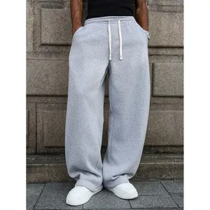 Detailed shot of mens grey loose sweatpants featuring adjustable drawstring and wide leg fit.