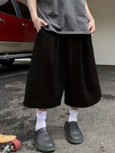 Detail view of men's solid black wide-leg cropped shorts, casual loose summer street style.