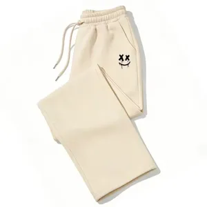 Pantalón de chándal beige holgado con gráfico de sonrisa gótica Y2K y cordón ajustable.