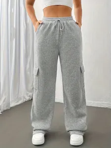 Dettaglio pantaloni della tuta cargo grigi larghi con vita elastica e tasche laterali.