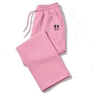 Detalle de pantalones de chándal rosas Y2K con gráfico de smiley XX y cordón ajustable.