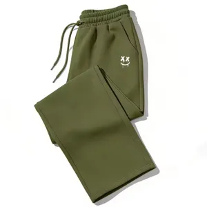 Vista detallada del bonito estampado de smiley gótico en pantalones de chándal verdes.