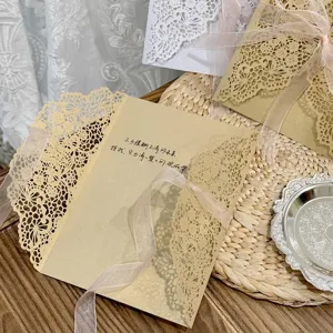 Gros plan d'une enveloppe d'invitation en papier kraft dentelle avec ruban rose