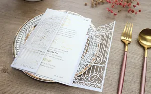 Detalle de invitación de boda blanca cortada con láser y elegante lámina de oro